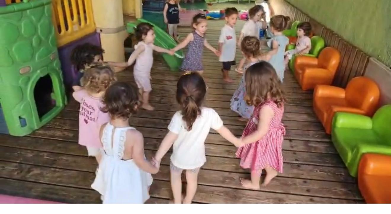 ילדים רוקדים במעגל בחצר הגן